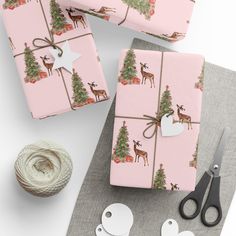 wrapping paper with deer and christmas trees on it next to scissors, twine and yarn