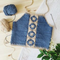 a crocheted blue top sitting on top of a table next to some yarn