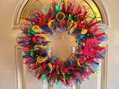 a colorful mesh wreath on the front door with a red heart cut out of it