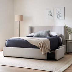 a bed sitting on top of a wooden floor next to a white dresser and lamp