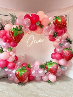 a strawberry balloon arch with pink and red balloons