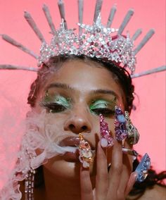 a woman in a tiara with feathers on her head and nails painted green, white and pink