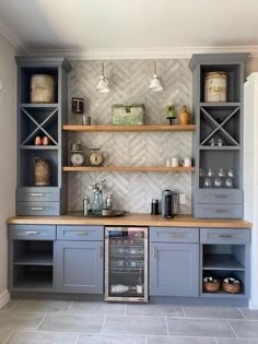 a kitchen with gray cabinets and shelves filled with dishes on top of counter tops next to a wine fridge