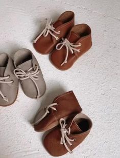 three pairs of baby shoes with laces on them