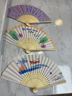 three hand fans sitting on top of a marble counter