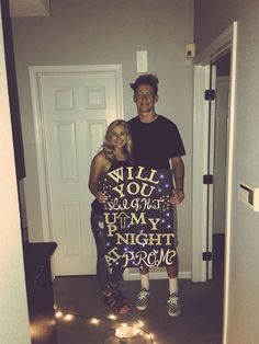 a man and woman standing next to each other holding a sign that says will you laugh at my night prom?