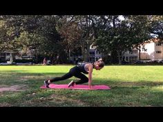 a woman is doing yoga on a pink mat in the middle of a grassy area