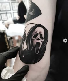 a person with a black and white tattoo on their arm wearing a grime mask