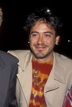 two men are smiling for the camera while wearing suits and tie dyes at an event