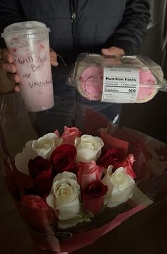 a bouquet of roses is being held by a person holding a plastic cup with a message on it