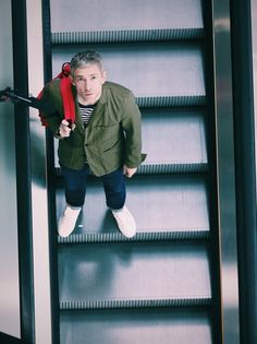 a man standing on top of an escalator holding a red object in his hand