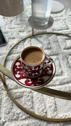 a cup of coffee sitting on top of a saucer next to a cell phone