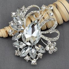 a crystal brooch sitting on top of a piece of wood next to a ring