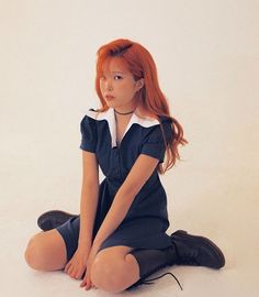 a young woman sitting on the floor with her legs crossed and red hair in pigtails