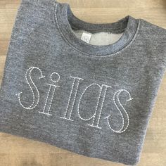 a t - shirt with the word stitchs on it sitting on top of a wooden table