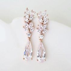 two pairs of pink and clear crystal earrings on top of a white cloth covered surface