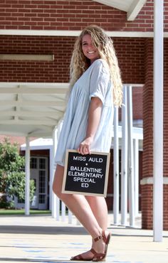 a woman is holding a sign in front of a building