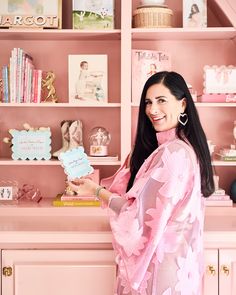 a woman standing in front of a pink bookcase holding a sign that says, i love you