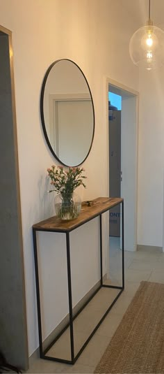 a room with a mirror, table and vase on the floor