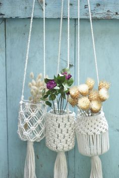 three macrame vases with flowers hanging from them