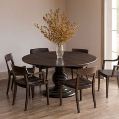 a dining room table with four chairs and a vase filled with flowers on top of it