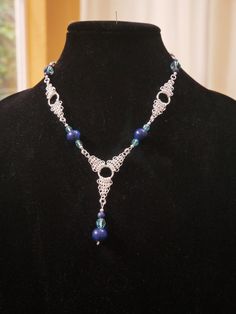 "Hundreds of 4.5mm silver plated brass rings are hand woven to create this stunning one-of-a-kind piece. The piece shown is the one you are buying.  Silver plate chain maille, Lapis Lazuli, and Swarovski Crystals come together in a sleek sophisticated necklace.  Rings this small start taking on a fabric feel when woven into chain mail - awesome tactile piece.  Central drop extends 2 1/2\" from main chain. Necklace is  18\" from clasp to clasp. 3\" silver extender chain allows you to wear the piece nestled at the base of your throat or longer to keep up with your wardrobe changes.  Silver plate Spring Ring clasp." Bohemian Chainmail Metal Jewelry, Elegant Sterling Silver Chainmail Necklace, Lapis Crystal, Brass Rings, Chain Maille, Pretty Jewelry, Chain Mail, Brass Ring, Copper Pendants