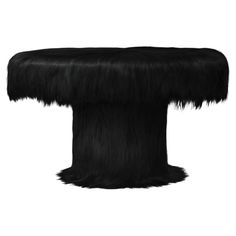 a black table with fur on it and an oval shaped base in the middle, against a white background