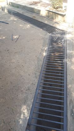 a metal grate sitting in the middle of a dirt field next to a tree