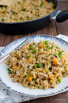 a close up of a plate of food with rice and vegetables on it next to a skillet