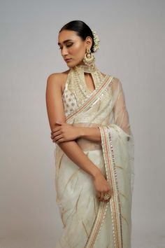 Editor's Note Radiate timeless beauty in this beautiful organza sari set, where subalpine detailing paired with a halter neck blouse creating a captivating look for special occasions. The blend of traditional craftsmanship and modern sensibilities makes it a must-have for those seeking a perfect balance between traditional yet evergreen style. Organza Blouse With Cutdana For Reception, Wedding Blouse With Sheer Dupatta For Diwali, Wedding Blouse With Sheer Dupatta For Eid, Festive Organza Blouse Piece For Transitional Season, Festive Transitional Organza Blouse Piece, Designer Cutdana Organza Blouse, Designer Organza Blouse With Cutdana, Anarkali Saree Style Organza Blouse, Traditional Drape Organza Blouse With Cutdana