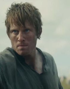 a close up of a person wearing a green shirt and looking at the camera with a serious look on his face