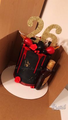 a birthday cake in a box with red and black decorations on the top that says 25