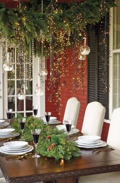 a dining room table decorated for christmas with garland hanging from the ceiling