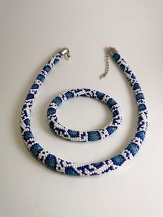 two pieces of blue and white beaded necklaces on a white surface with a silver chain