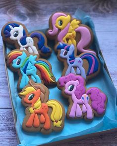 there are many decorated cookies in the shape of pony's and ponies on this blue box