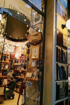 there is a store front with many books on the shelves and people sitting in the window