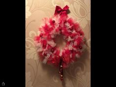 a red and white wreath hanging on the wall with a candy cane in front of it