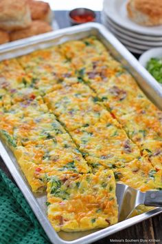 an egg casserole is in a pan on a table with other dishes and utensils