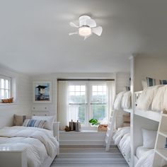 a bedroom with bunk beds and windows in the wall, along with white furniture on both sides