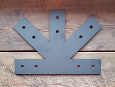 a metal arrow sign mounted to the side of a wooden wall with holes in it