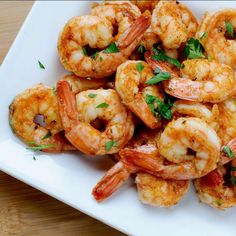 a white plate topped with cooked shrimp and garnished with parsley on top