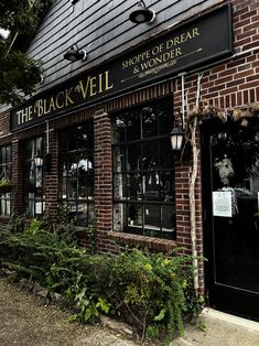 the black veil storefront is brick and has plants growing out of it's windows