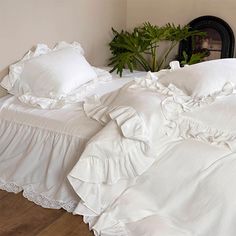 an unmade bed with white linens and ruffled bedspread on wooden floor