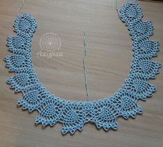 a blue crocheted necklace is on a table