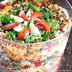 a salad with tomatoes, lettuce and other toppings in a glass dish