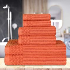 a stack of orange towels sitting on top of a wooden table