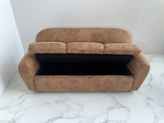 a brown couch sitting on top of a white floor next to a wall with a black pillow