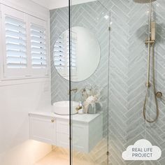 a bathroom with a walk in shower next to a white sink and mirror on the wall