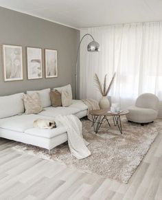 a living room filled with white furniture and decor on top of a hard wood floor