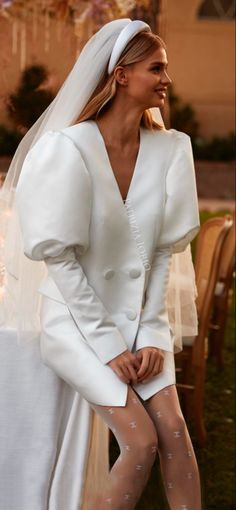 a woman in a white dress and veil is sitting on a chair with her legs crossed